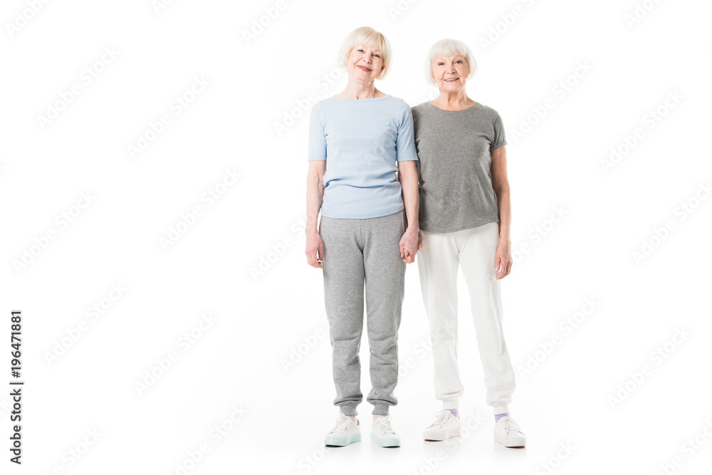 Two smiling senior sportswomen standing isolated on white Two smiling senior sportswomen standing isolated on white