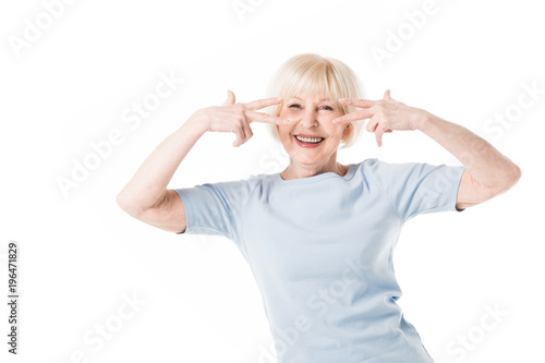 Smiling senior woman gesturing with fingers isolated on white