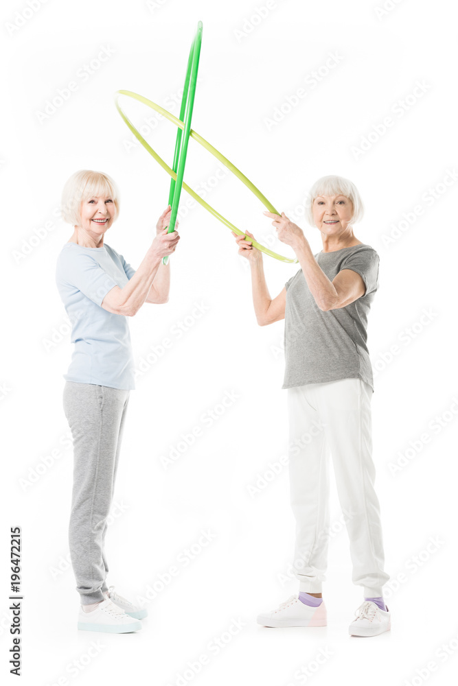 Senior sportswomen holding hula hoops isolated on white