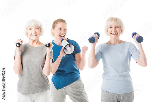 Two sportswomen with dumbbells and coach with megaphone isolated on white