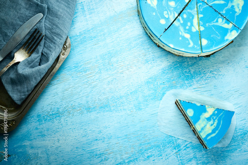 sliced cake and piece of mousse cake with blue glaze on the white-blue wooden background © vitaliymateha