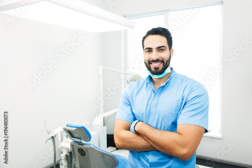 Portrait of hadsome dentist doctor wears blue uniform  indoor shot in modern dentist office