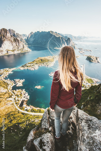 Woman tourist traveling in Norway standing on cliff mountain aerial view Lofoten islands lifestyle exploring concept adventure outdoor summer vacations