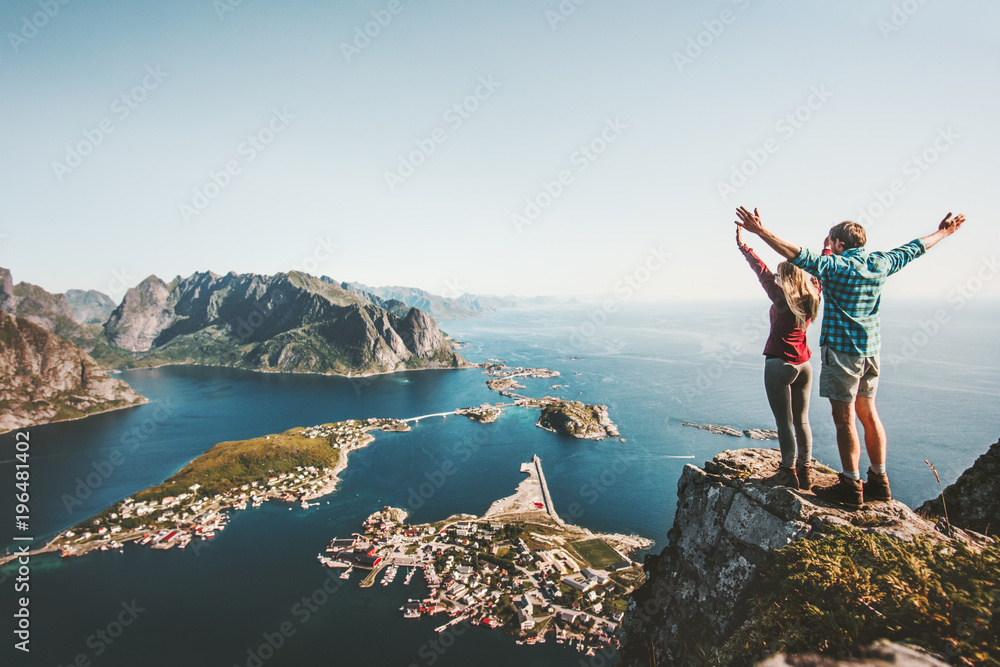 Happy Couple love and travel raised hands on cliff in Norway man and woman family travelers lifestyle concept summer vacations outdoor Lofoten islands - obrazy, fototapety, plakaty 