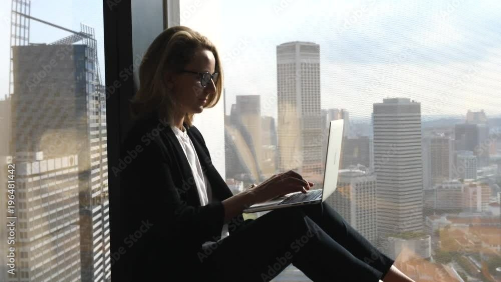 Business Woman Using Laptop Computer Sitting At Office Window With City View Business Woman Using Laptop Computer Sitting At Office Window With City View