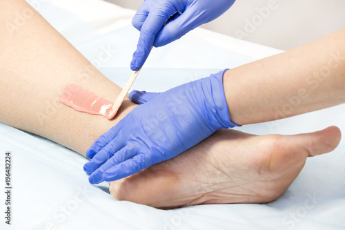 The process of classical wax depilation of female limbs in the beauty salon. 