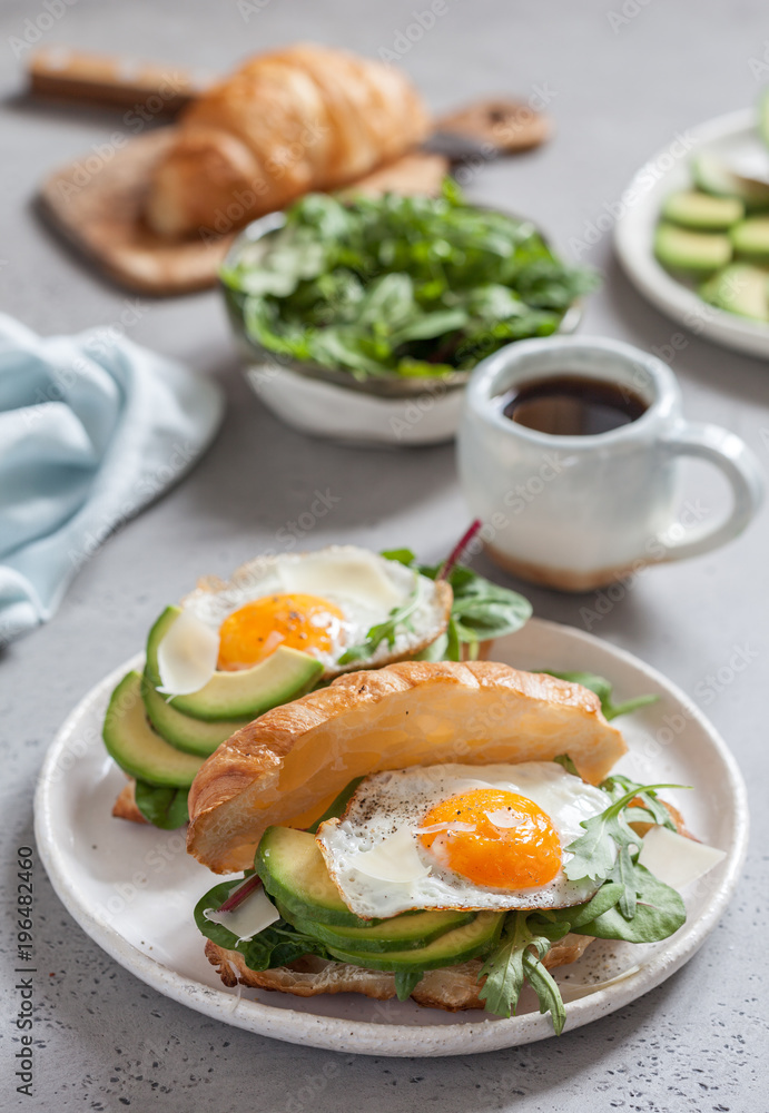 Breakfast with Croissant sandwiches with Fried Egg, Salad Leaves and avocado