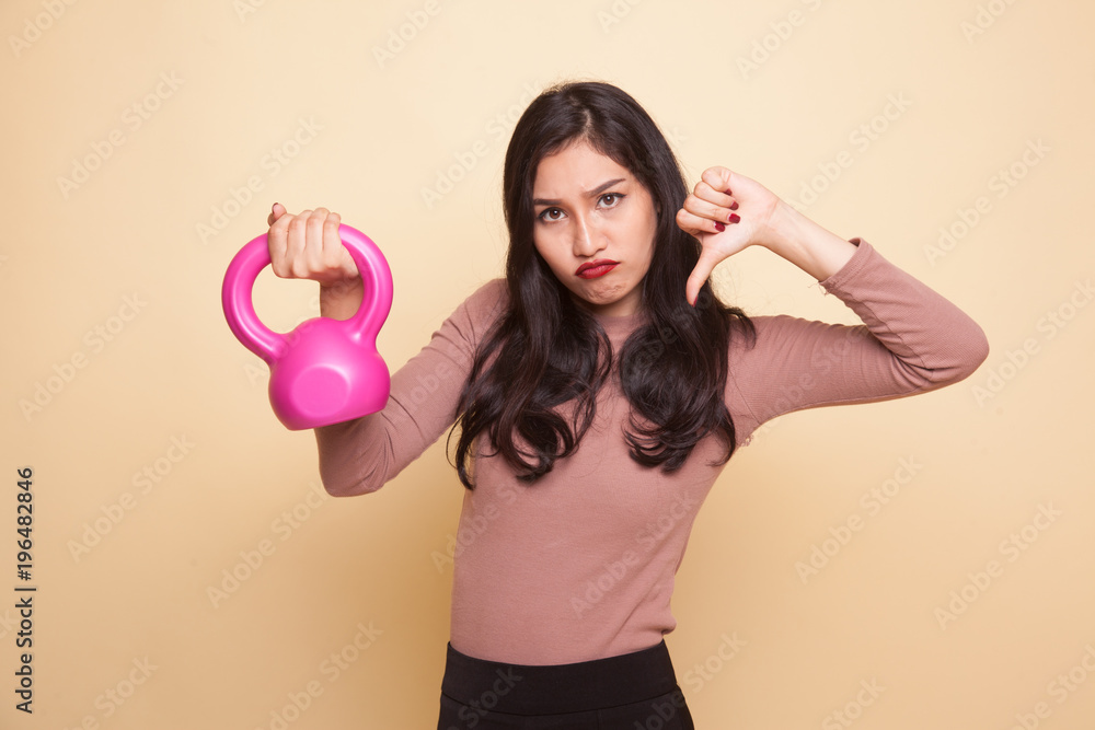 Unhappy Asian woman thumbs down with dumbbells. Unhappy Asian woman thumbs down with dumbbells.