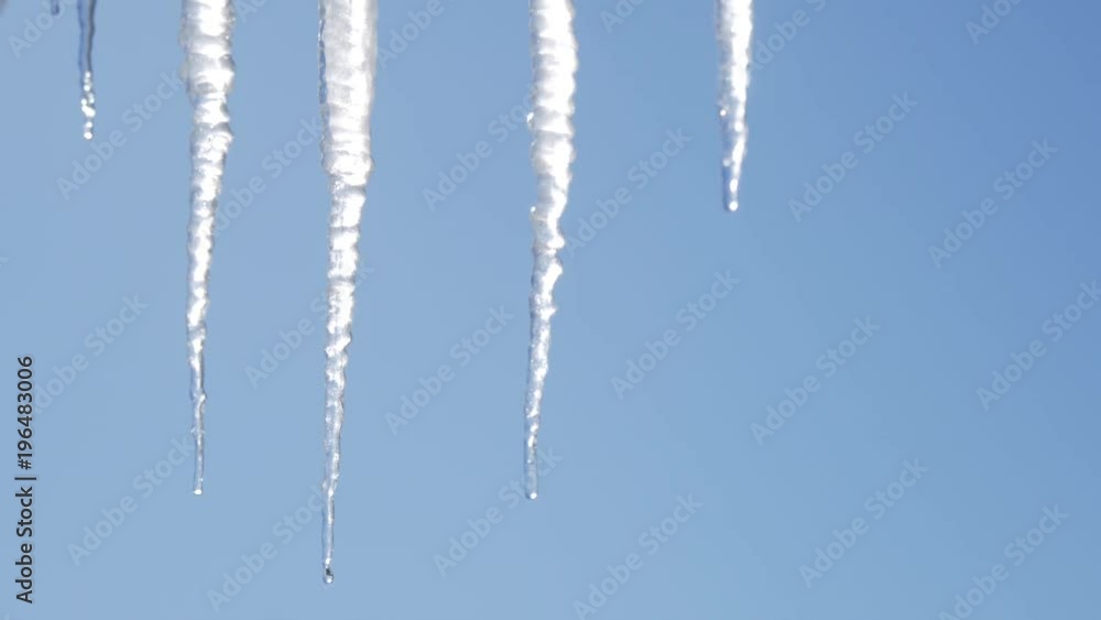 Many beautiful icicles melt on the roof at the end of winter and water drops are fall down. Spring is comming concept. Many beautiful icicles melt on the roof at the end of winter and water drops are fall down. Spring is comming concept.
