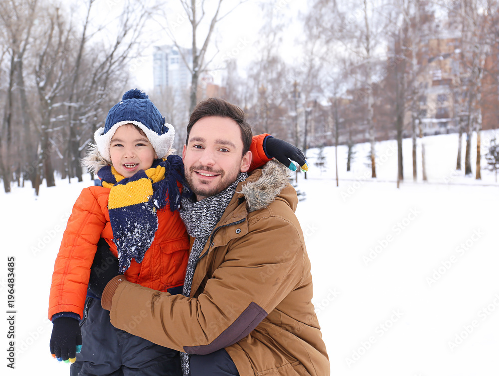 Happy man with son in snowy park on winter vacation