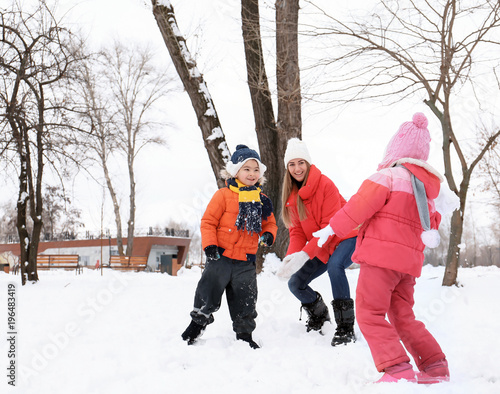 Happy family playing in snowy park on winter vacation