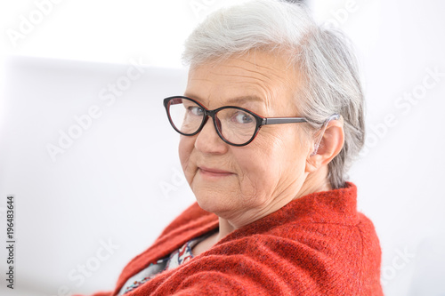 Mature woman with hearing aid indoors