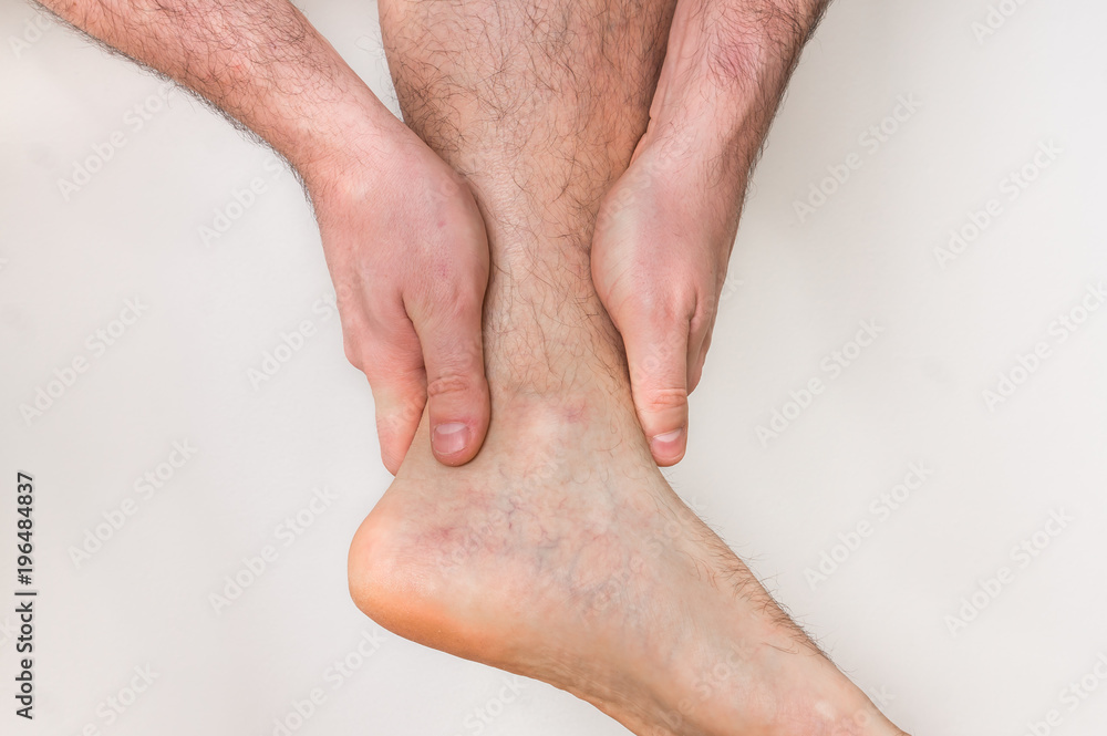 Fototapeta premium Man with ankle pain holding his aching leg