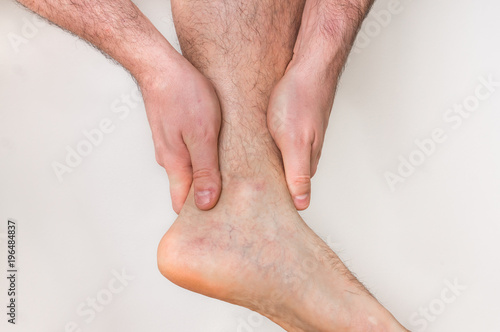 Man with ankle pain holding his aching leg