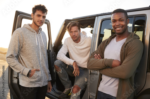 Three male friends on road trip looking at camera from jeep #196486686