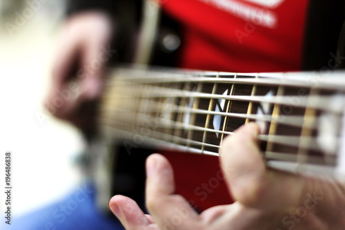 close up on the fingers of musician playing bass guitar on the stage