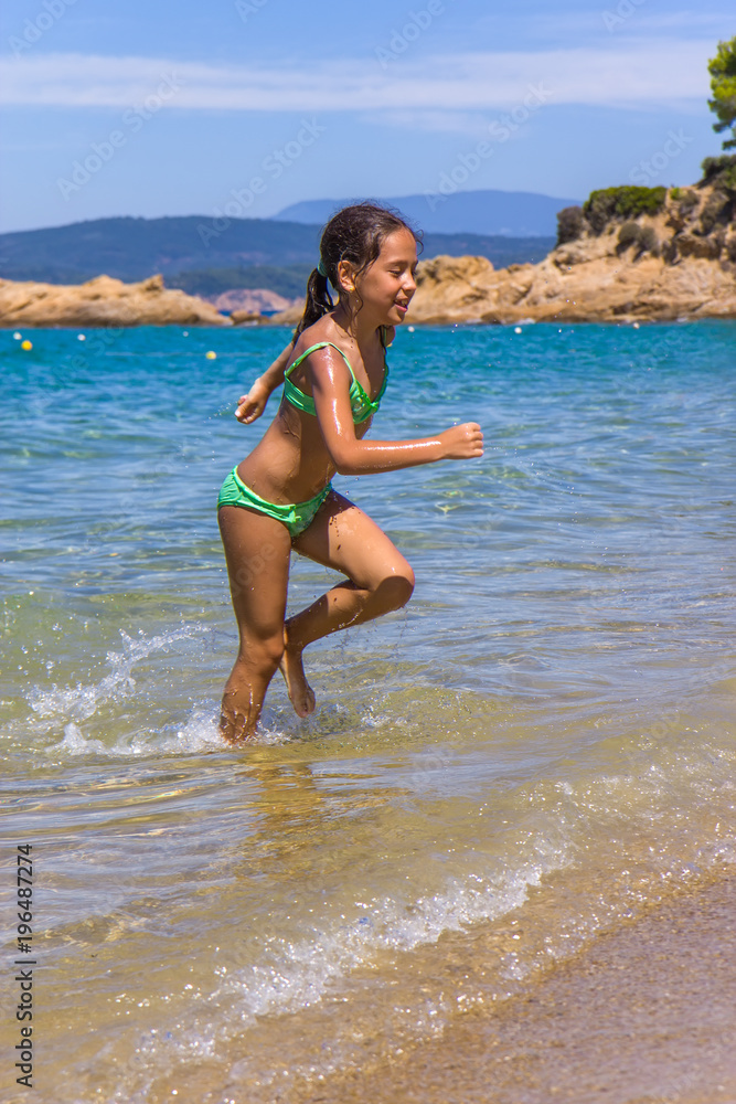 Fototapeta premium Girl running and splashing on the shallow beach