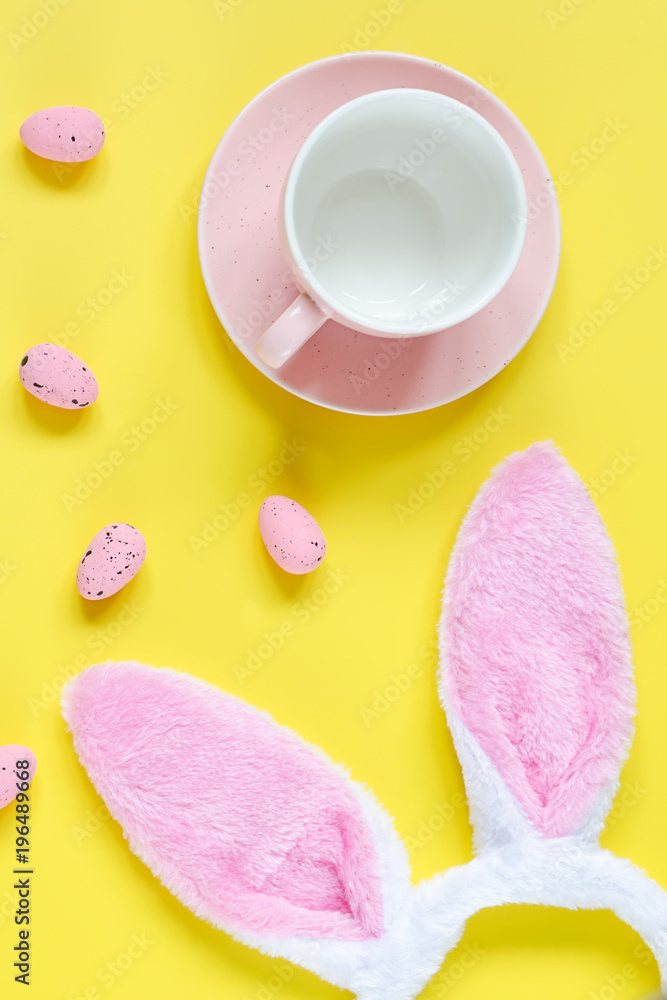 Easter holiday background with empty cup for coffee, bunny ears and easter eggs