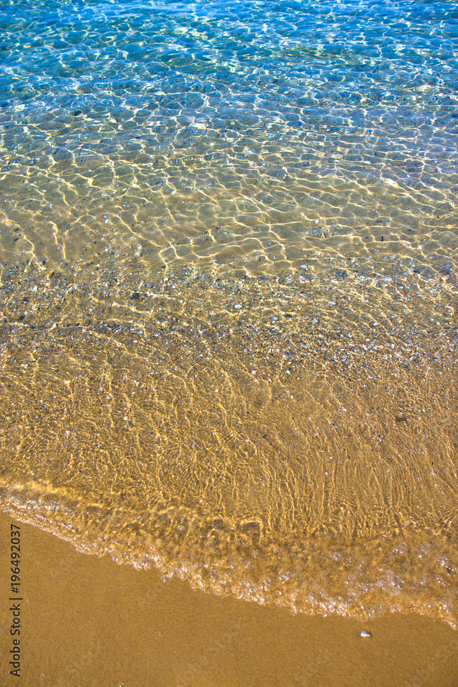 Seashore with blue water and orange sand and waves Seashore with blue water and orange sand and waves