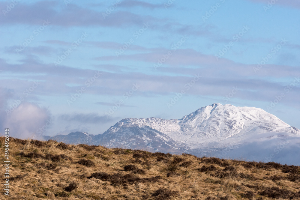Clouds clearing to reveal the peak of the snow covered Ben Lomond