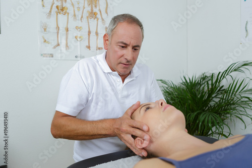 woman receiving head massage from physiotherapist in clinic