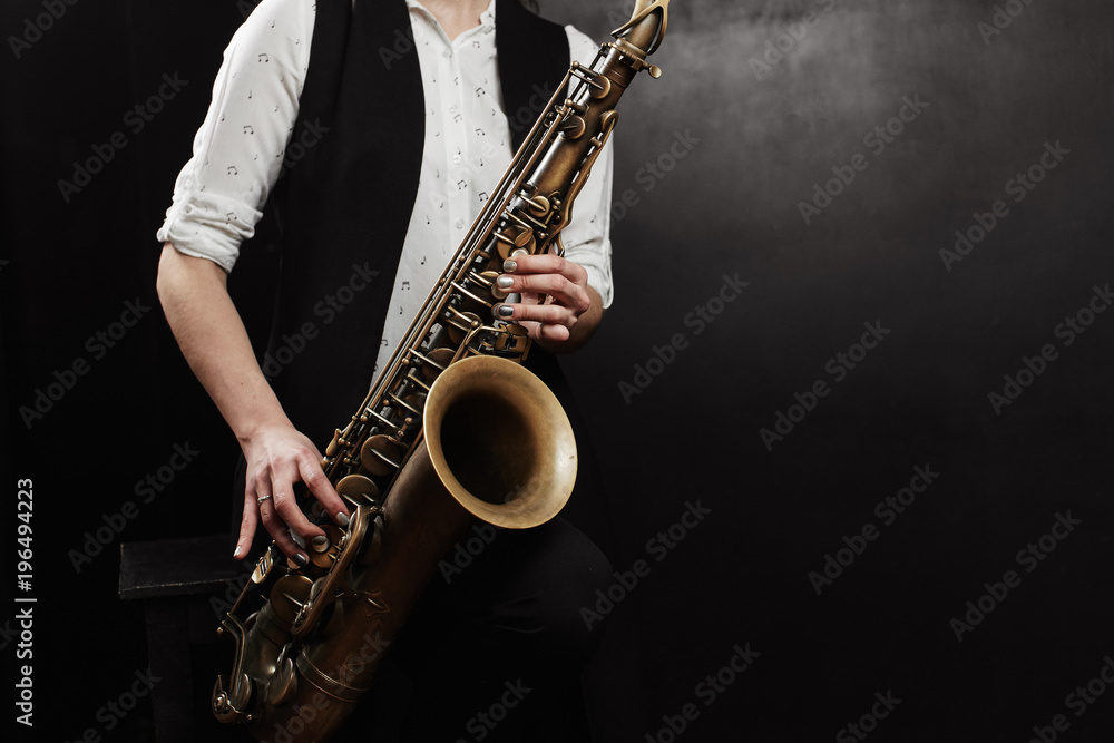 Naklejka premium Young woman with saxophone on black background