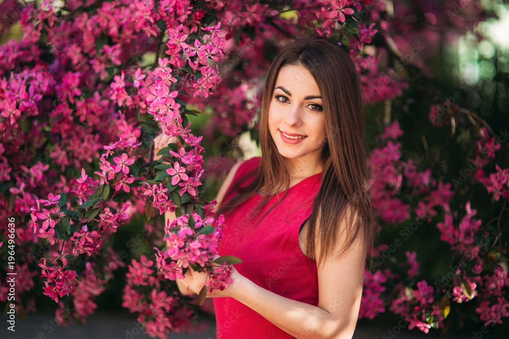 Young girl posing for a photo. Flowering pink trees in the background. Spring. Sakura Young girl posing for a photo. Flowering pink trees in the background. Spring. Sakura