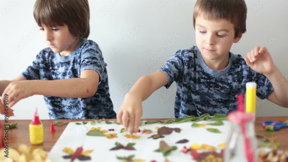 Sweet children, boys, applying leaves using glue while doing arts and crafts in school, autumn time Sweet children, boys, applying leaves using glue while doing arts and crafts in school, autumn time