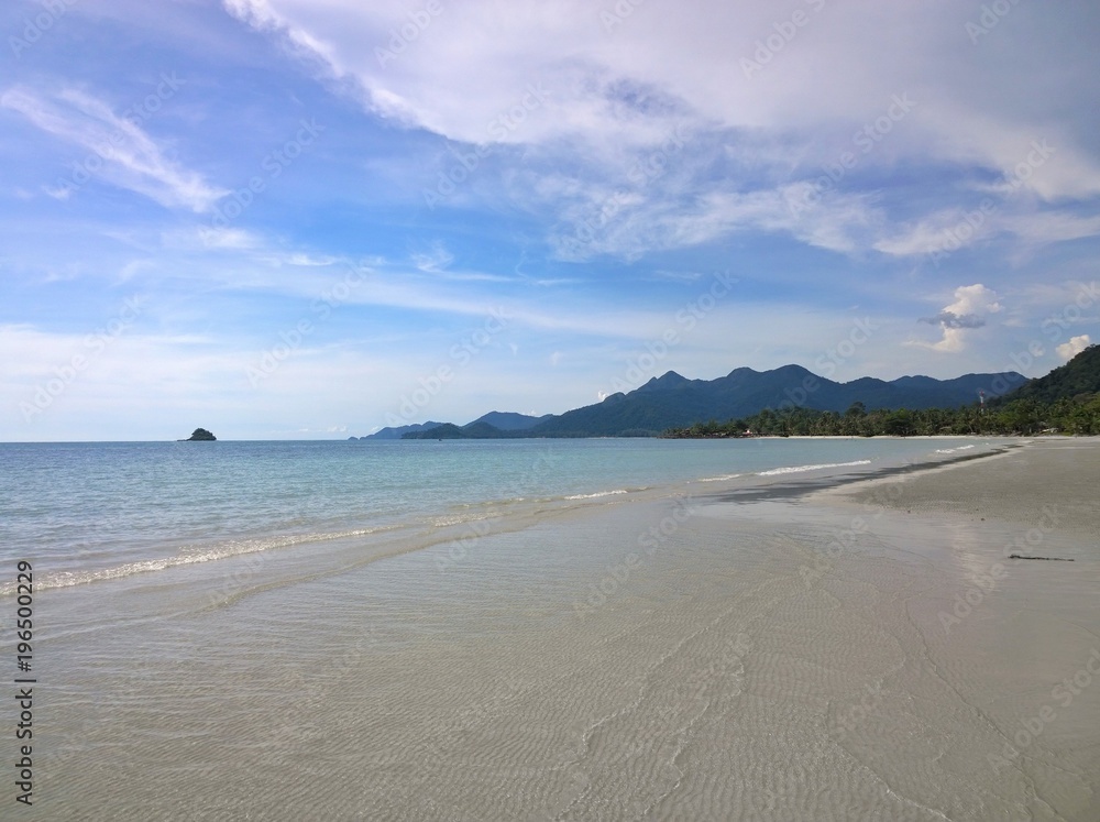 Fototapeta premium Blue sky and clouds over a tropical beach with green palm trees on Koh Chang island in Thailand