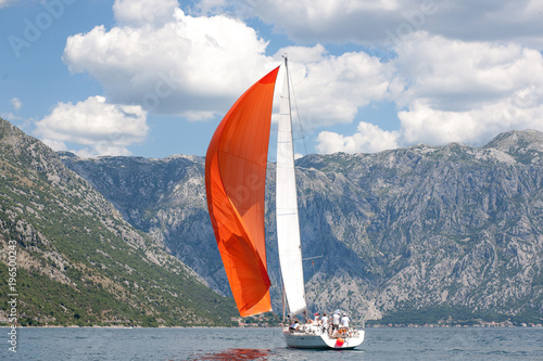 Sailboat with red sail on blue water on on boka bay photo