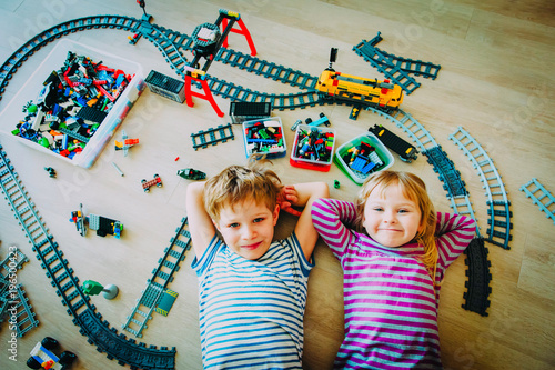 little boy and girl play with railroad and trains indoor