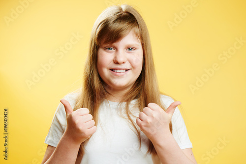 фотографія chubby redhead teen girl showing thumbs up standing on a yellow background