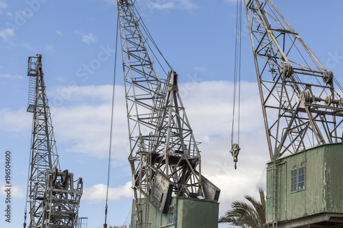 Three old cranes in port .