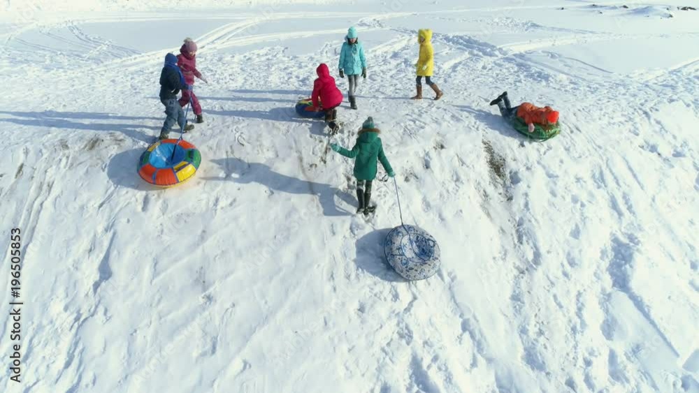 The children are playing and rolling down a hill on snow inflatable sled