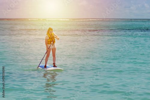 Beautiful woman paddling on the paddle board in the ocean