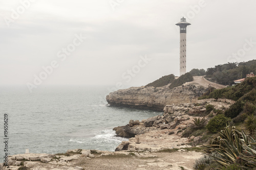 Lighthouse and cliffs in a cloudy day. Torredembarra, Costa Daurada, Catalonia, Spain.