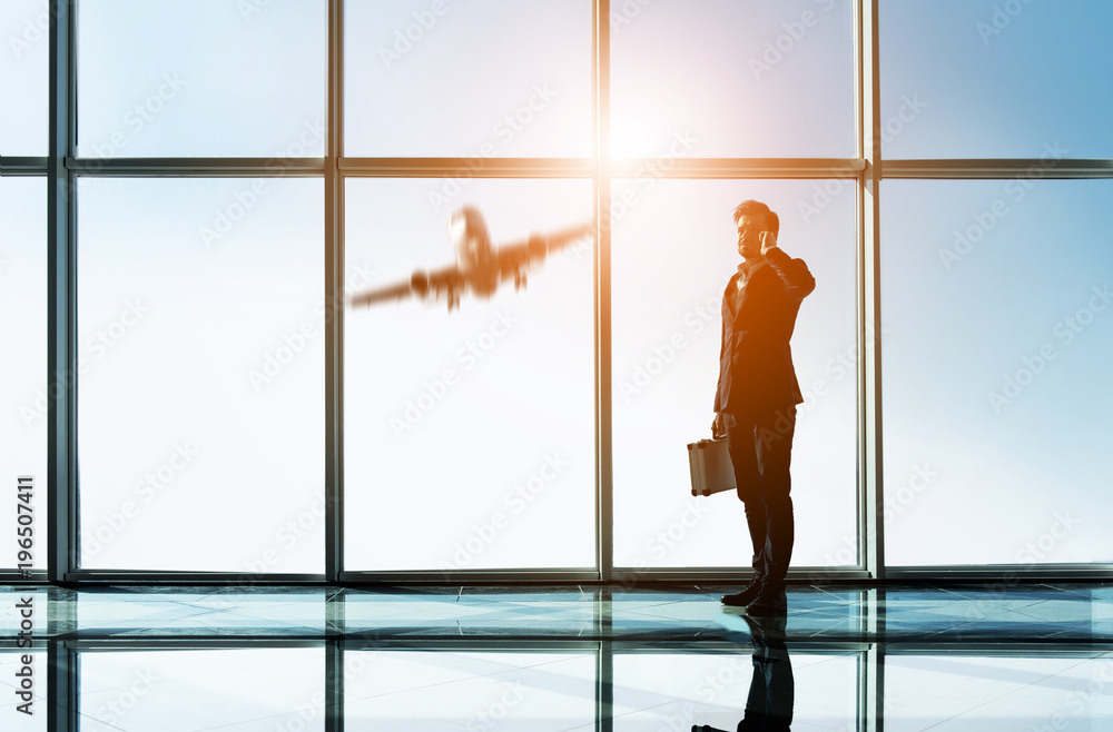 Silhouette view of young businessman is standing in modern office with panoramic windows Silhouette view of young businessman is standing in modern office with panoramic windows