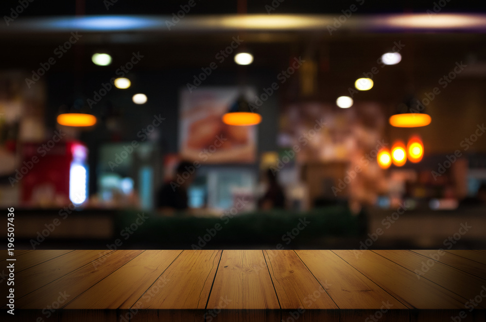 Empty wooden table top with blur coffee shop or restaurant interior background.