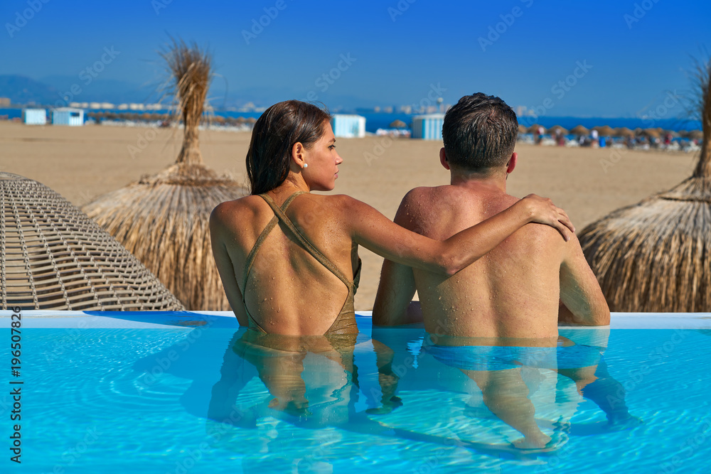 Tourist couple in infinity pool rear view Tourist couple in infinity pool rear view