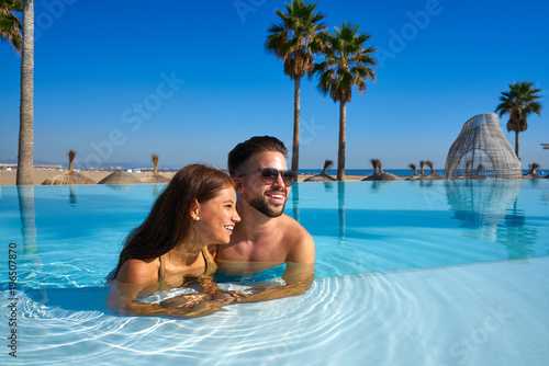 Tourist couple having bath in infinity pool