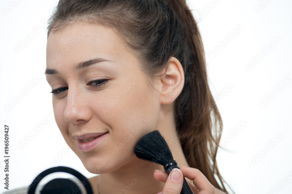 young and smiling woman applying powder on her face