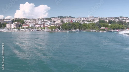 Lausanne city cinematic aerial shot. Camera flying over the lake and rising to discover the city in the background