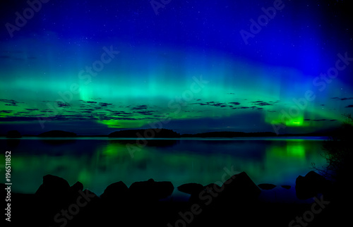 Northern lights dancing over calm lake. Farnebofjarden national park in Sweden.