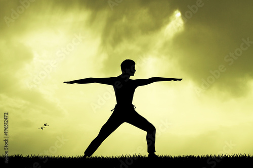 man doing yoga silhouette at sunset