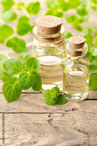 Oregano oil and fresh oregano leaves on the wooden table