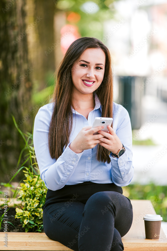 Young beautiful businesswoman drinks coffee and use cellphone Young beautiful businesswoman drinks coffee and use cellphone