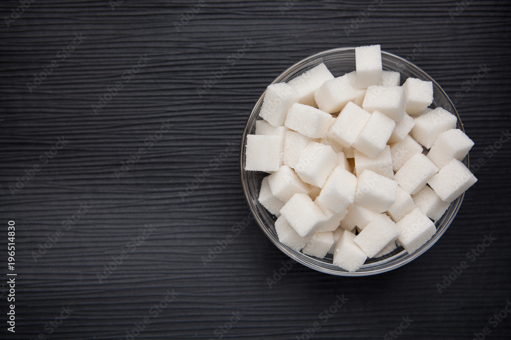 White sugar cubes in round bowl on black background White sugar cubes in round bowl on black background