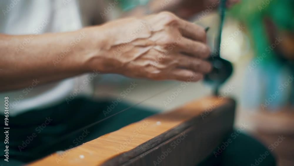 Roll focus on an elderly man's hands playing the dan bau in a street performance Roll focus on an elderly man's hands playing the dan bau in a street performance