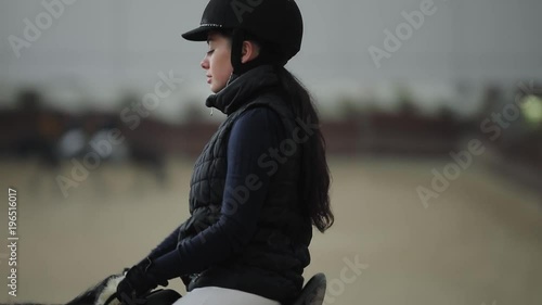 Professional horsewoman riding horse in a manege