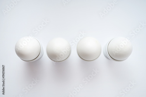 White eggs standing on egg cup isolated on white background, copy space. Row of boiled eggs in stand. Top view, flat lay. Healthy food concept